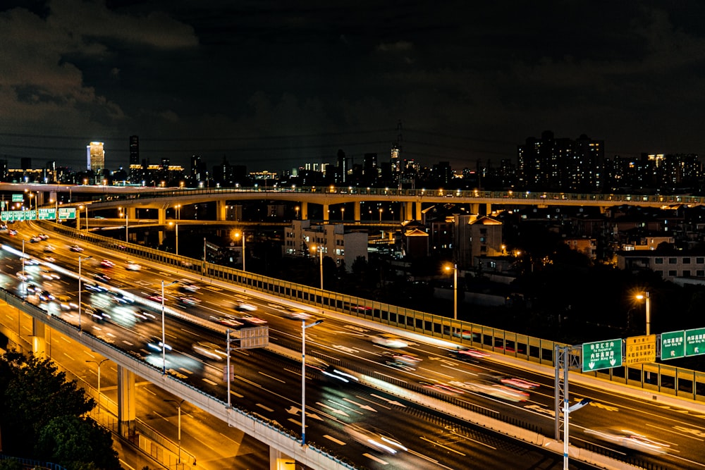 a night time view of a freeway with a bridge in the background