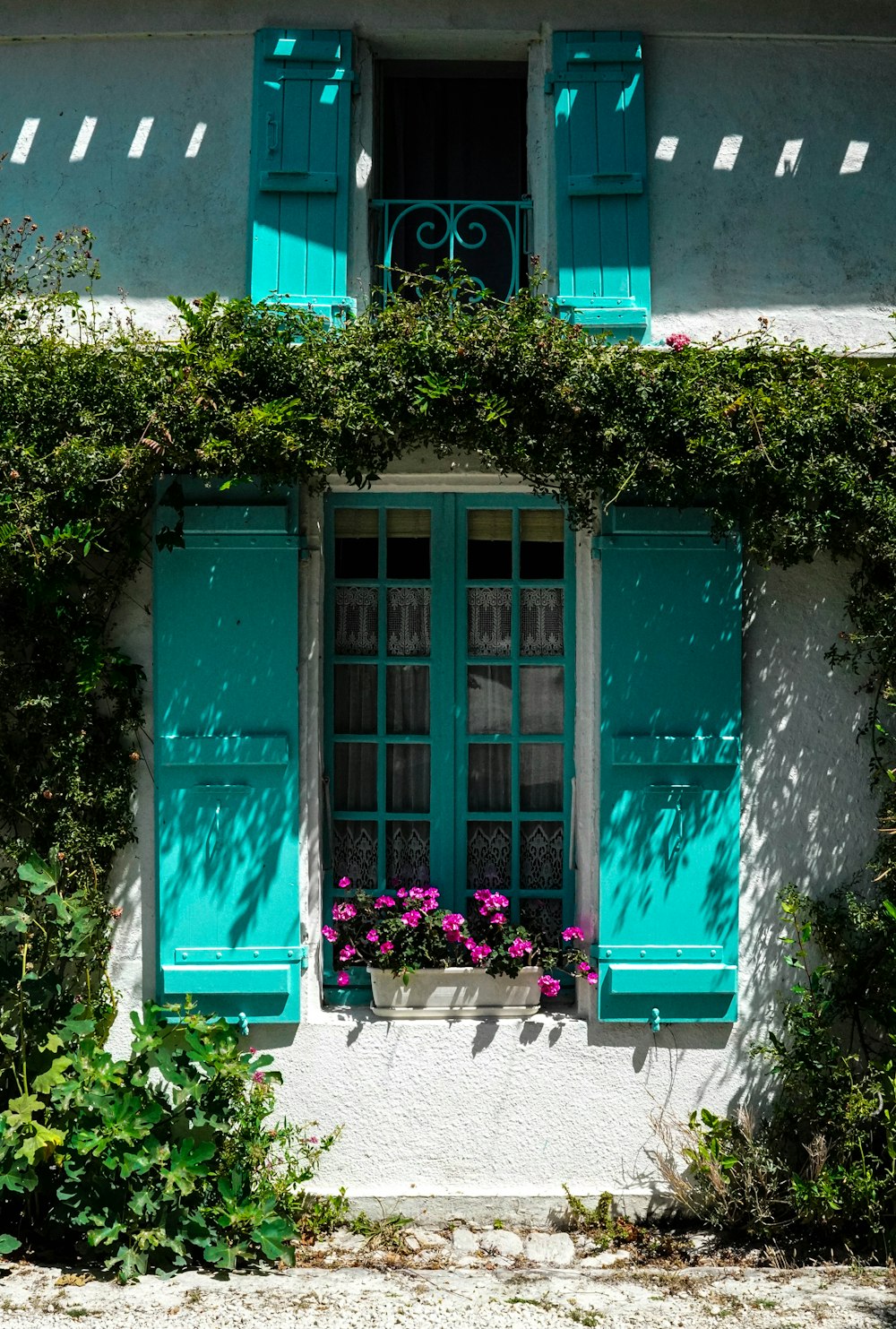 a window with green shutters and flowers in a window box