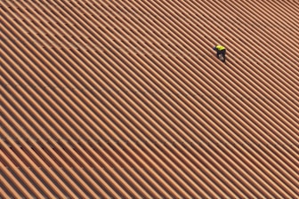 Skilled roofer repairing a damaged roof with safety gear in a residential neighborhood