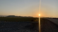 A panoramic view of a sunset over a winding mountain road.