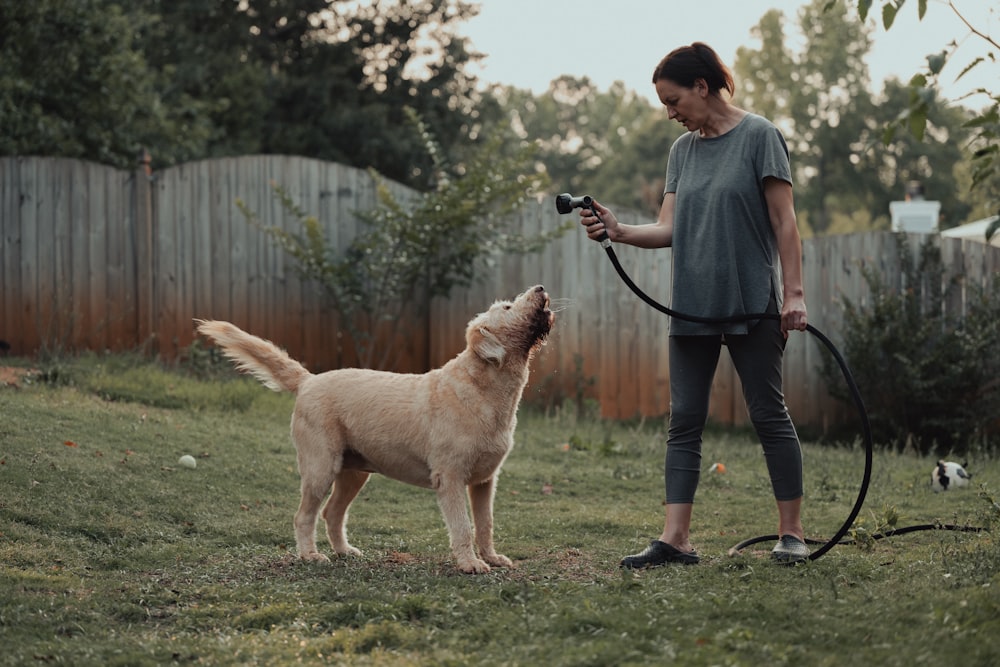 Una mujer sostiene una manguera a un perro