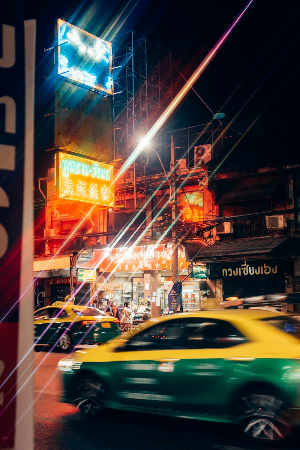 a green car driving down a street at night