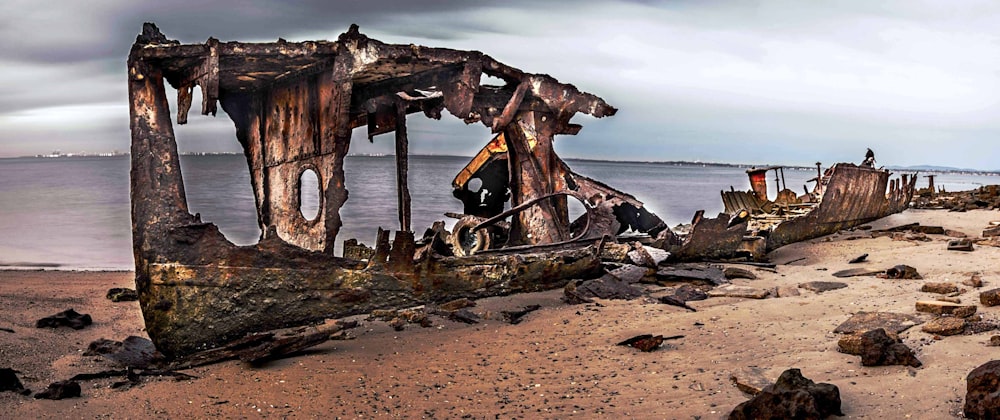 an old boat sitting on top of a sandy beach