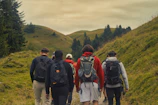 A group of friends trekking through lush green hills with backpacks and smiles.
