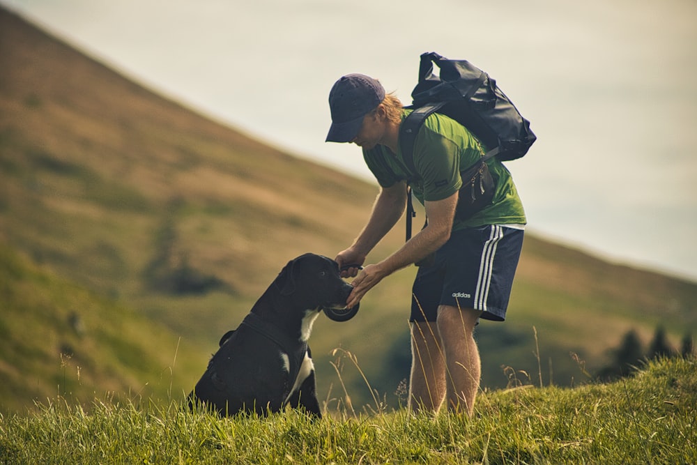 Un homme avec un sac à dos caressant un chien