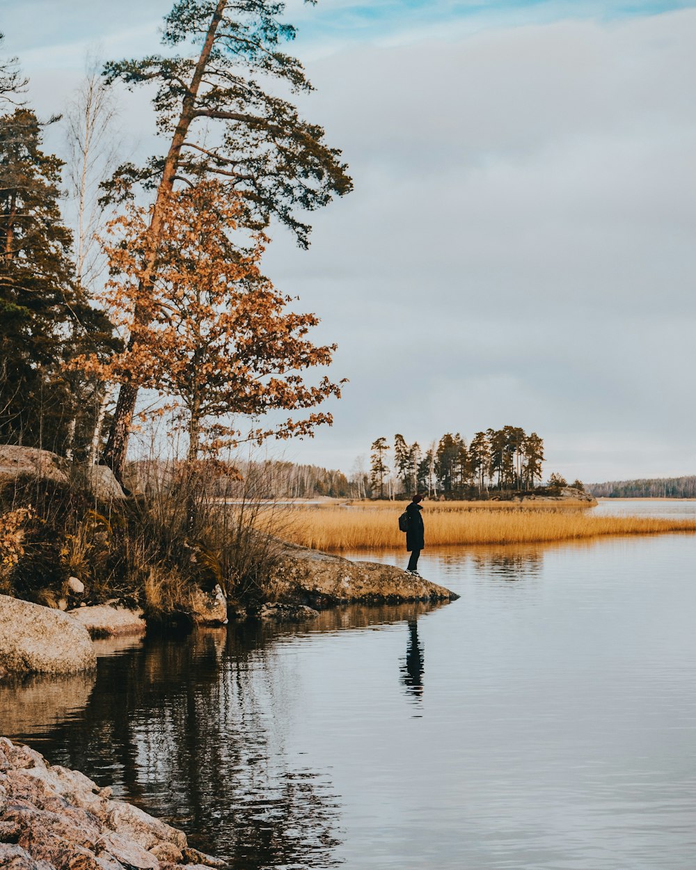 a man standing on a rock in the middle of a lake