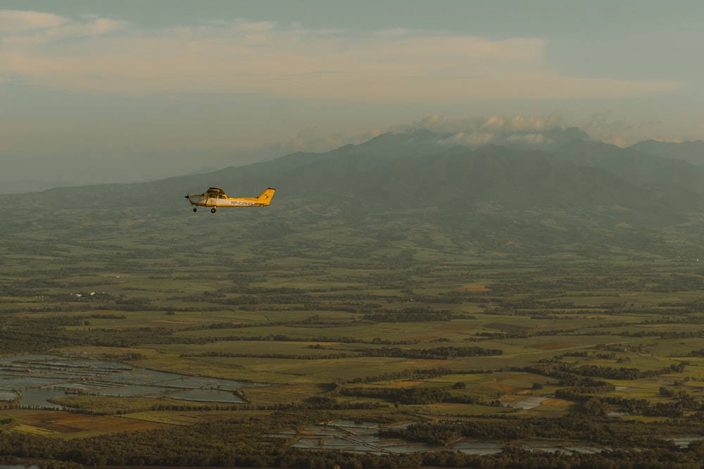 a small plane flying over a lush green field