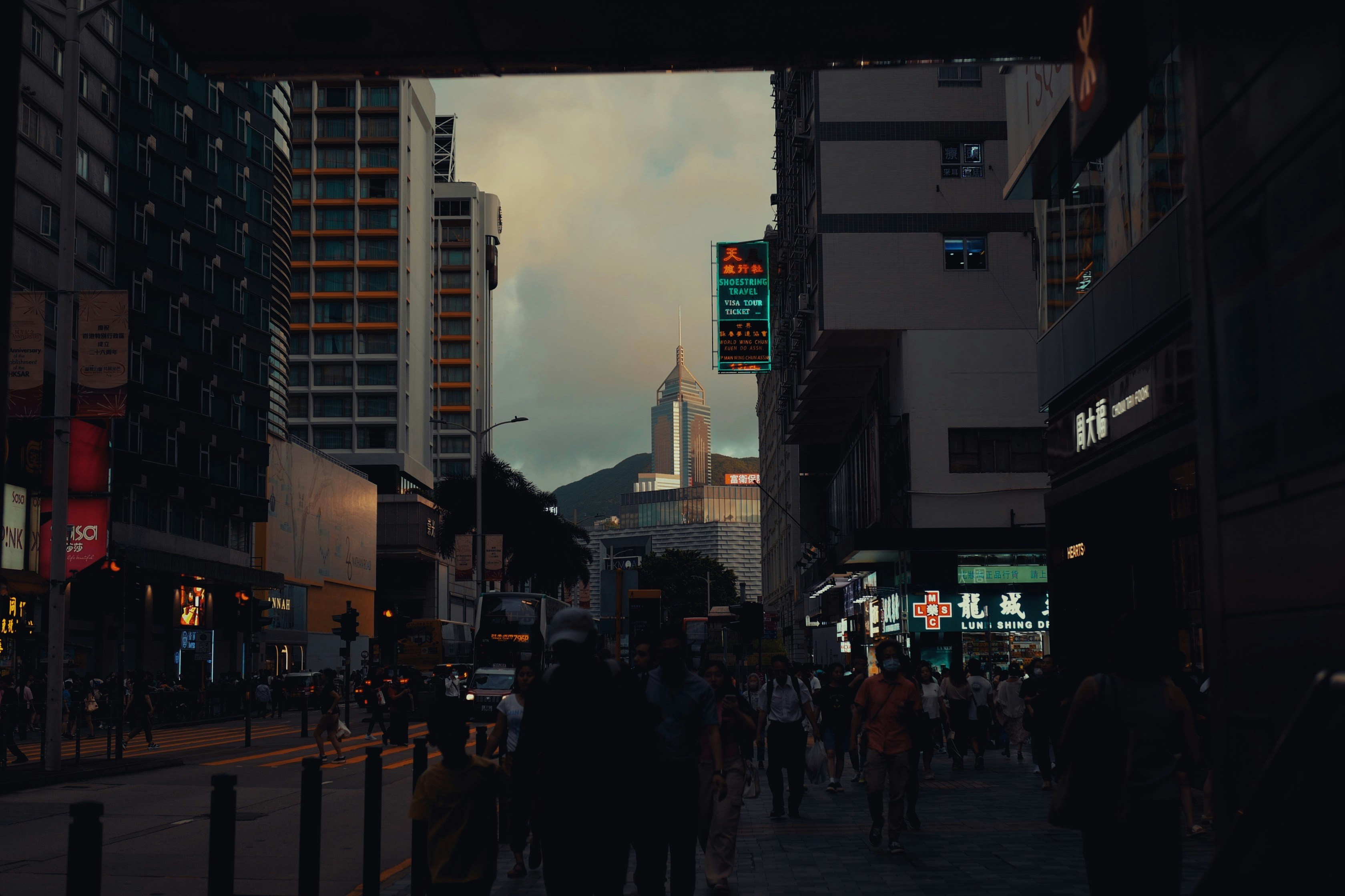 A group of people walking down a street next to tall buildings photo ...