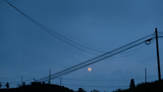 Night shot of energized transmission lines glowing softly under the moonlight.