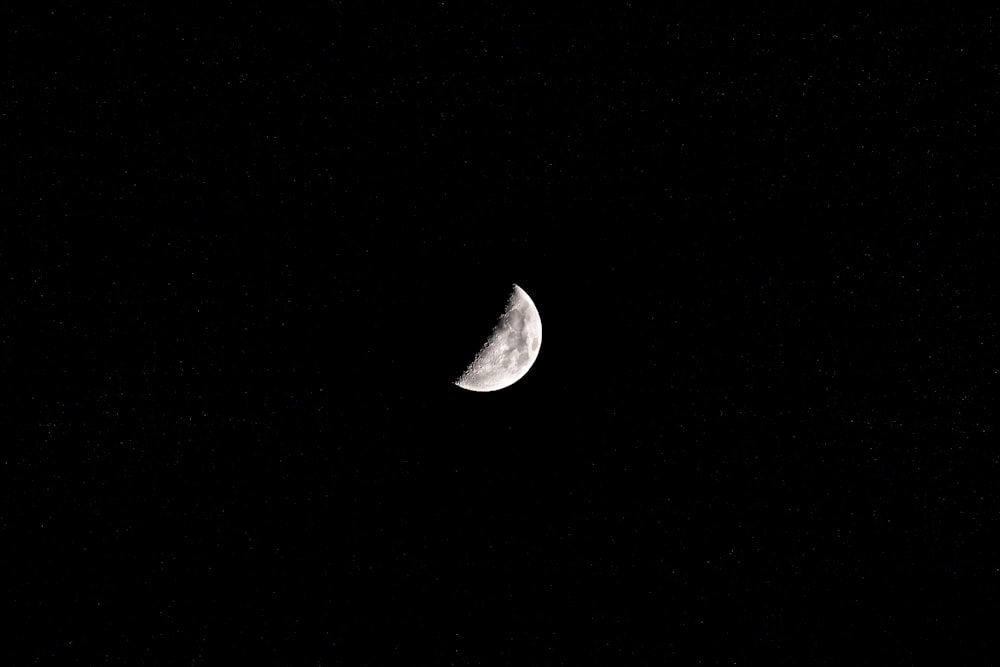 a half moon is seen in the dark sky