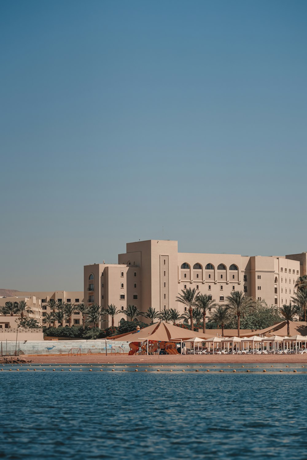 a large building sitting on top of a beach next to a body of water