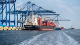 a large cargo ship in the water with a large crane in the background