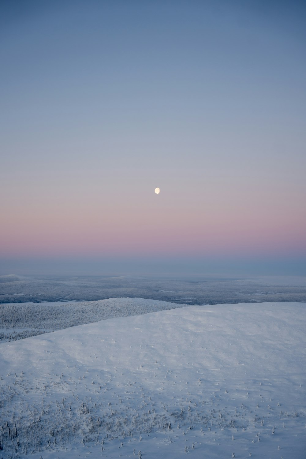 a full moon is seen over a snowy landscape