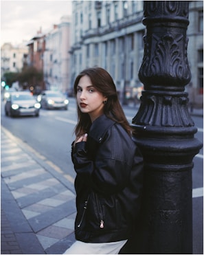 A young woman wearing a sleek Lumina Apparel jacket walking through a bustling city street at sunset.