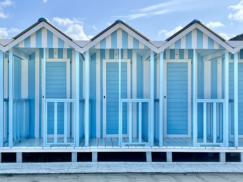 a row of blue beach huts sitting next to each other