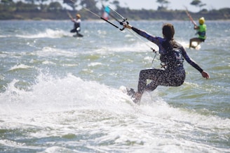 A group of kiteboarders riding the waves on a sunny day.