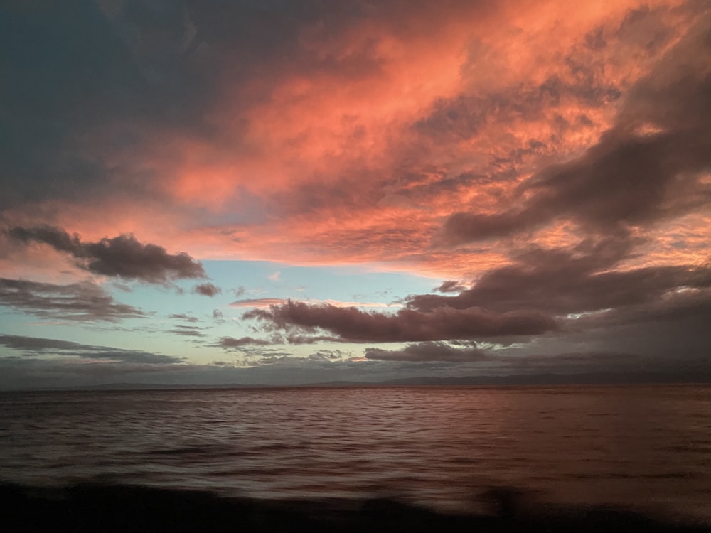 a sunset over a body of water with clouds in the sky