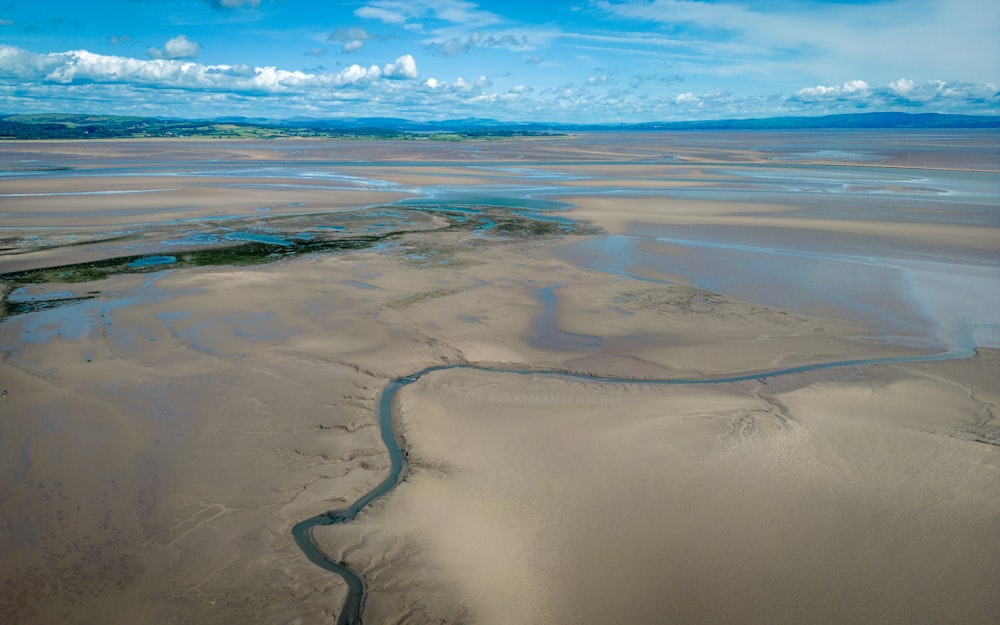 une rivière qui traverse une plage de sable sous un ciel bleu