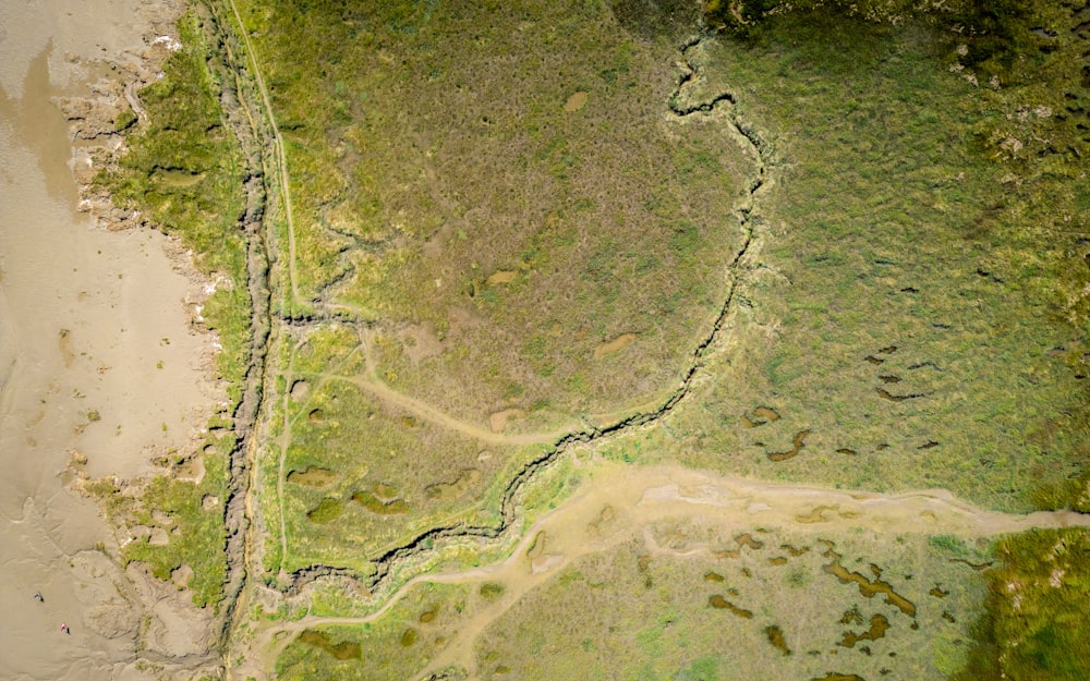 an aerial view of a river running through a lush green field