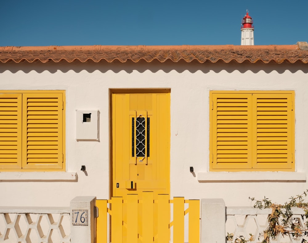 a white house with yellow shutters and a red roof