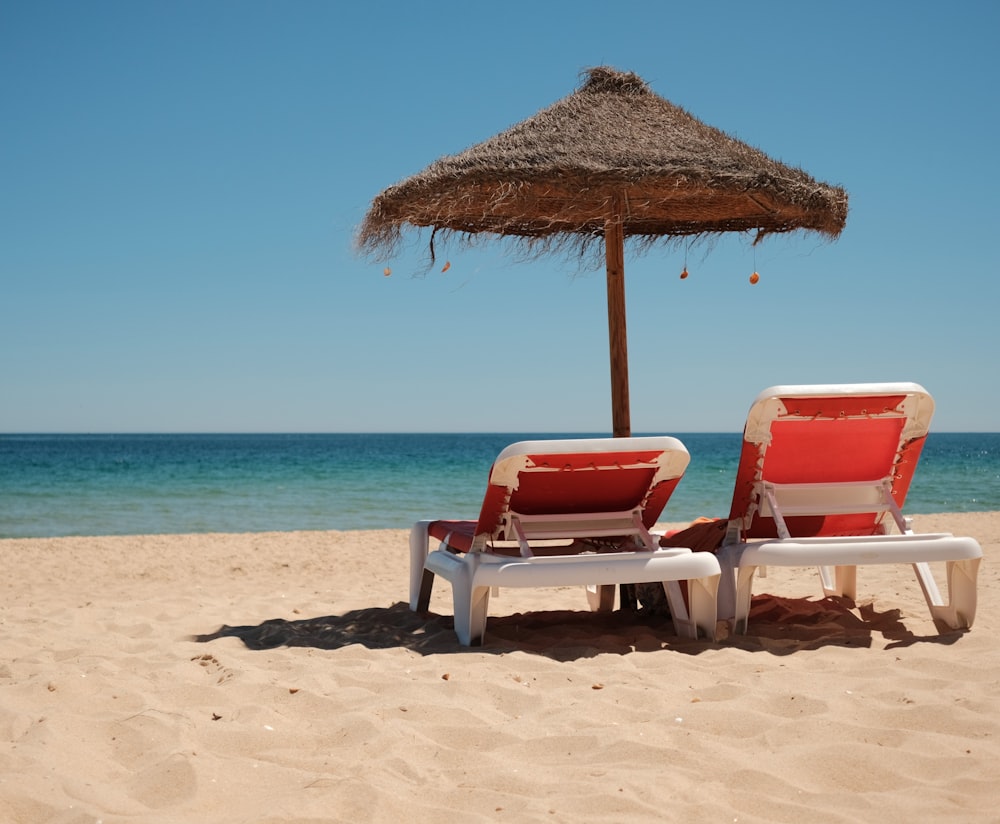 a couple of lawn chairs sitting on top of a sandy beach