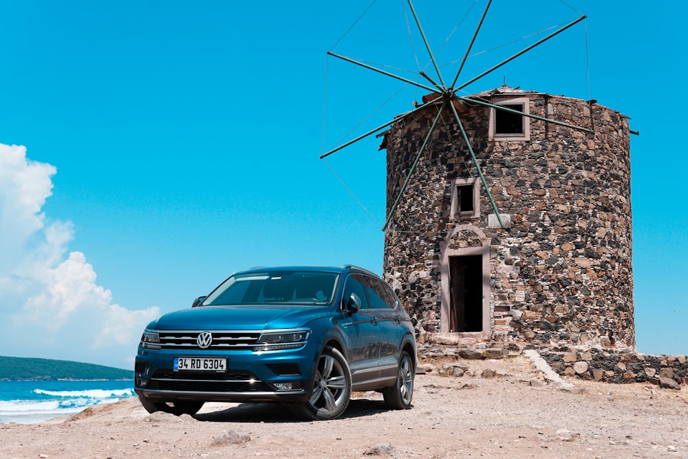 a blue volkswagen suv parked in front of a windmill