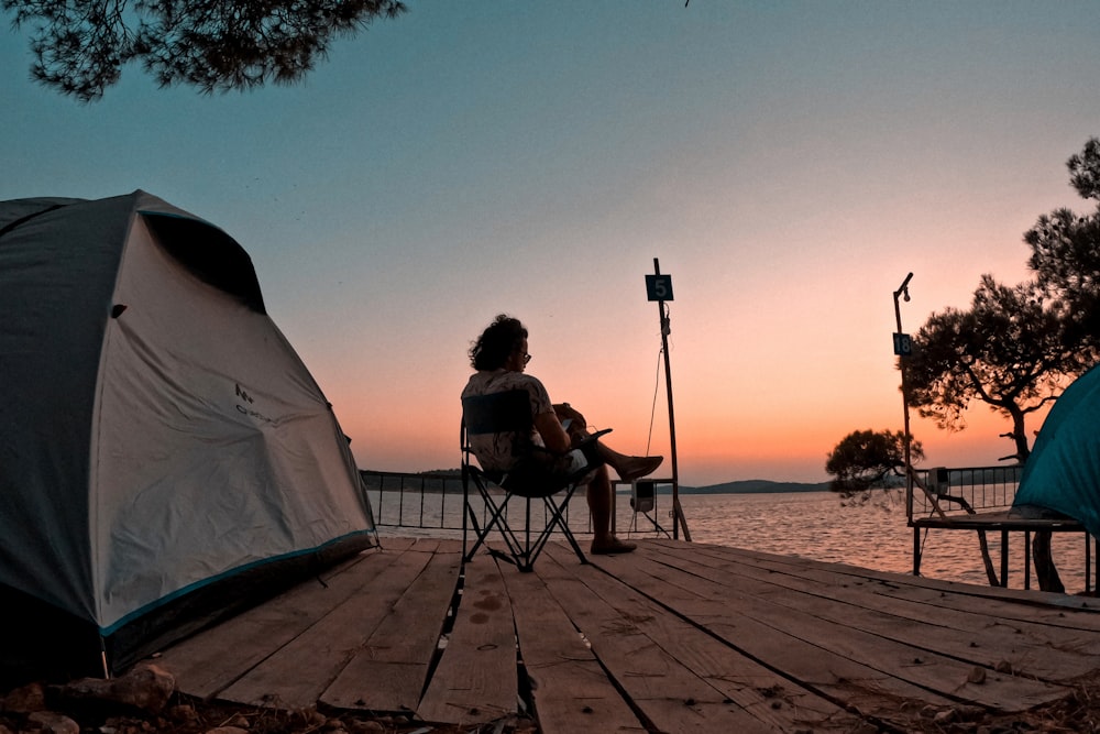 a person sitting in a chair next to a tent