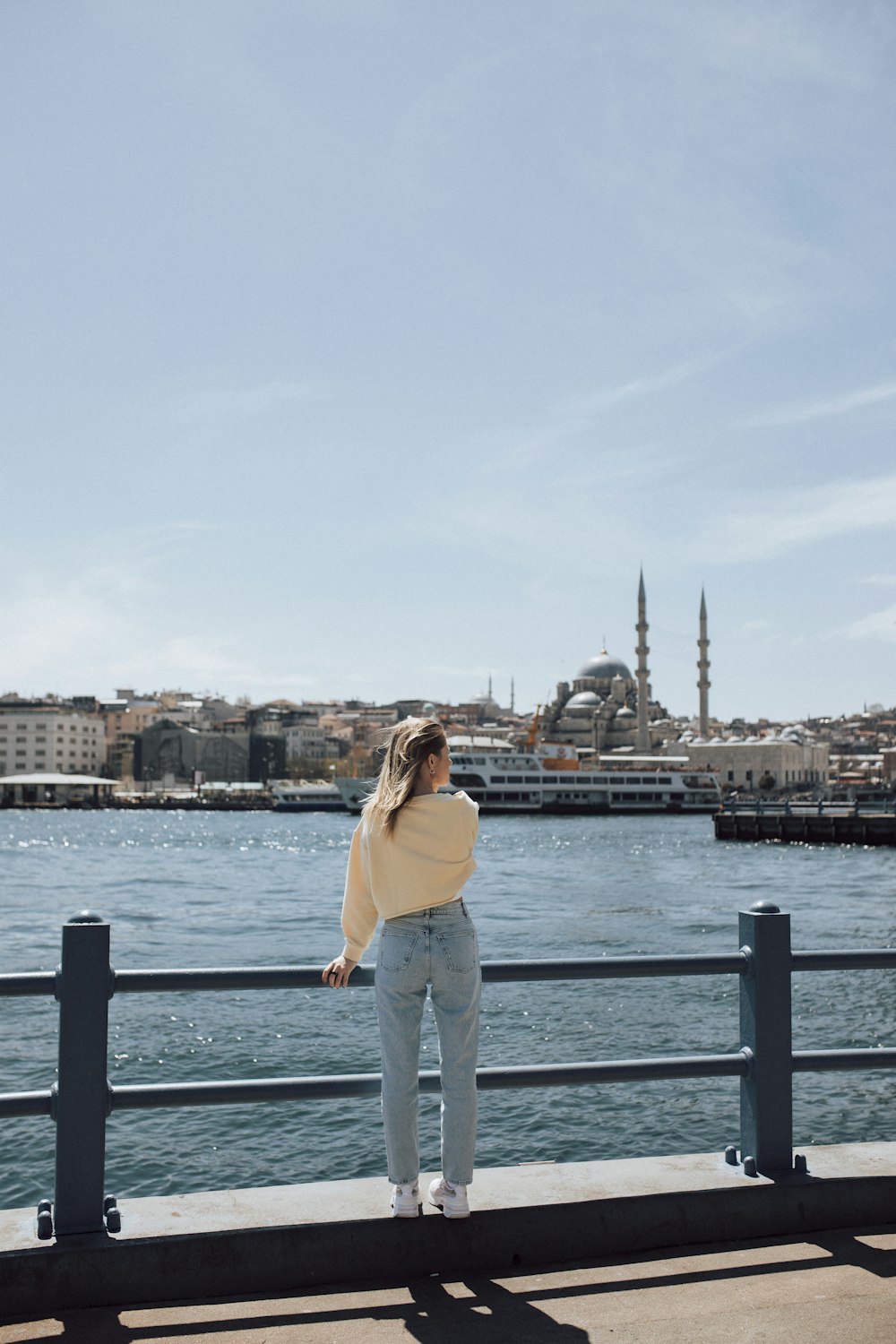 a woman standing on a pier looking at the water