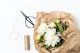 Hands tying a natural jute twine around a bouquet wrapped in eco-friendly kraft paper