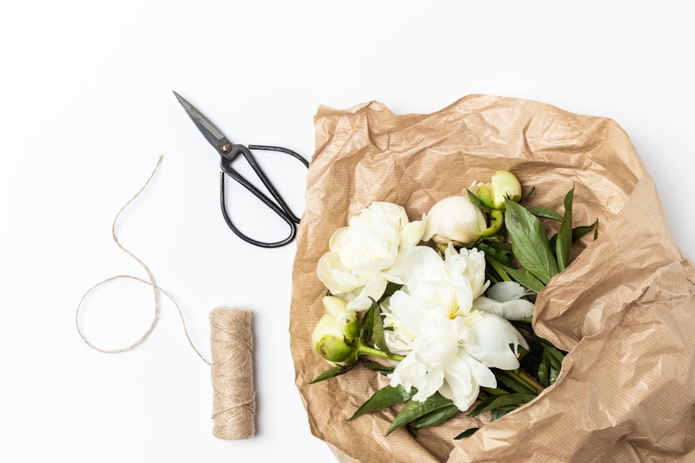 a bunch of flowers sitting in a bag next to a pair of scissors