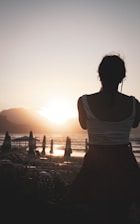 a woman standing on top of a beach next to the ocean