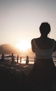 a woman standing on top of a beach next to the ocean