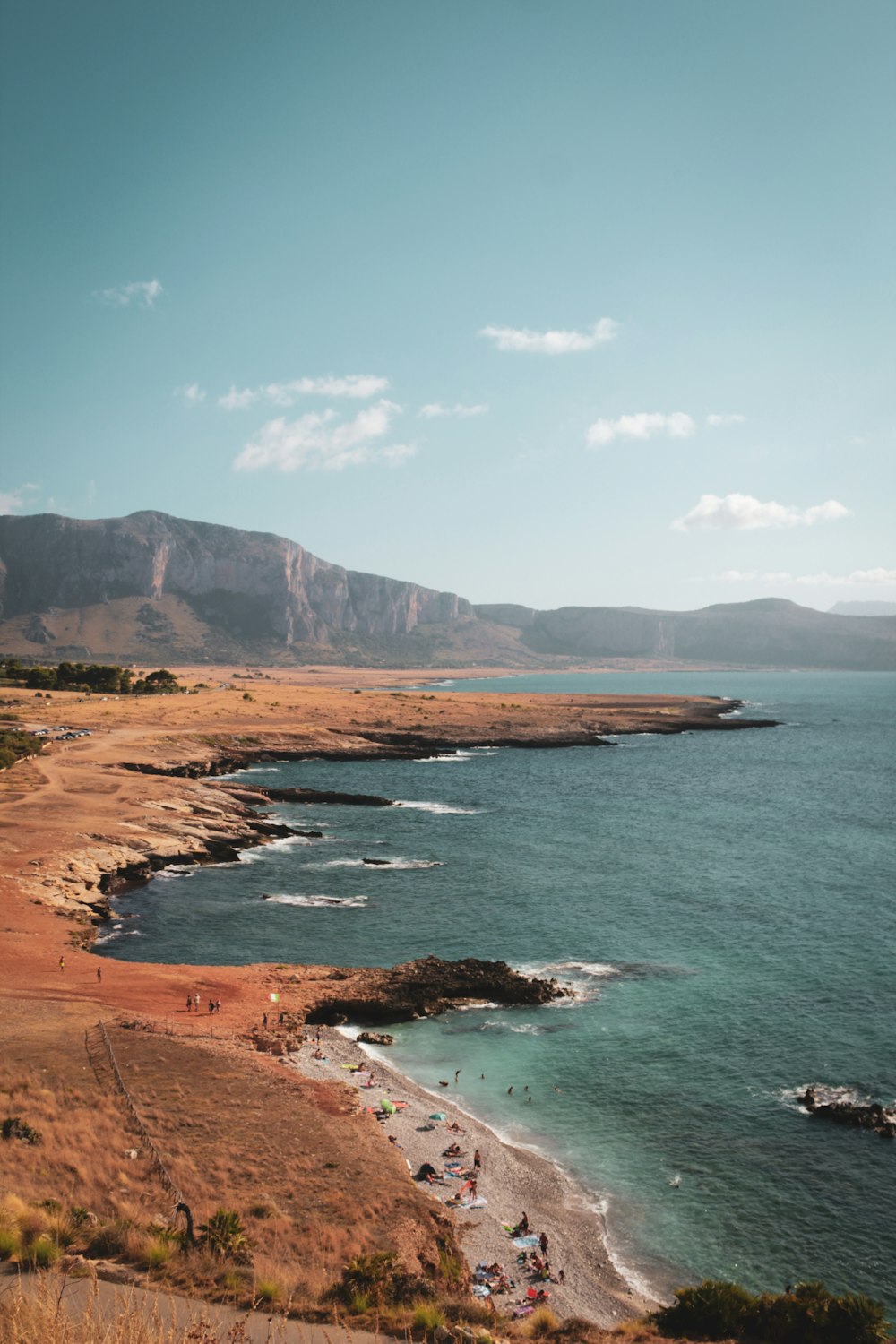 a beach with a body of water and mountains in the background