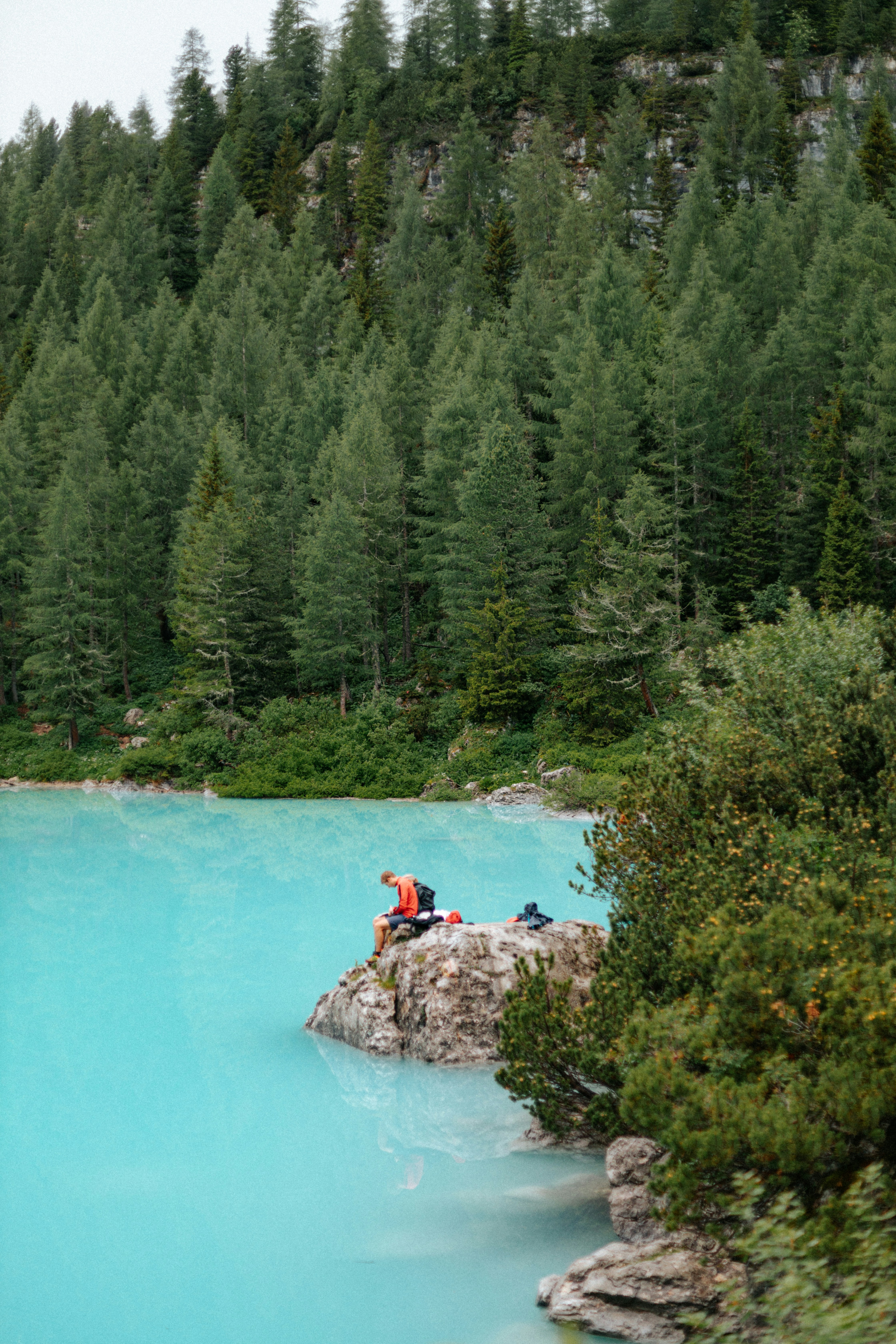 a group of people sitting on a rock in the middle of a lake