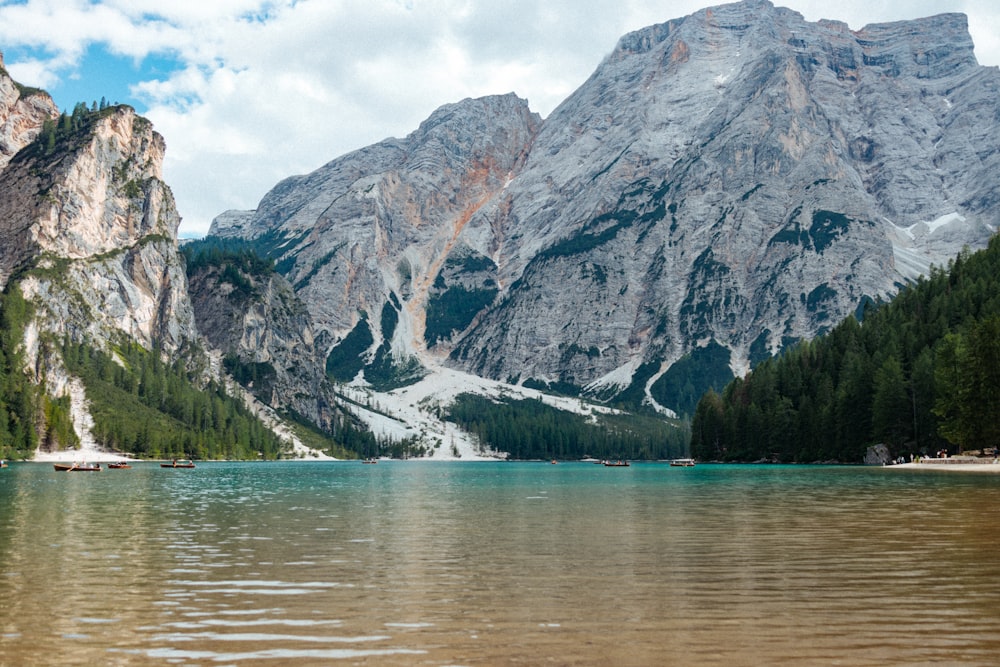 a lake surrounded by mountains under a cloudy sky