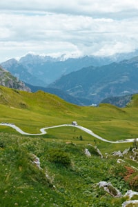 A car descending a winding mountain road through green valley terrain
