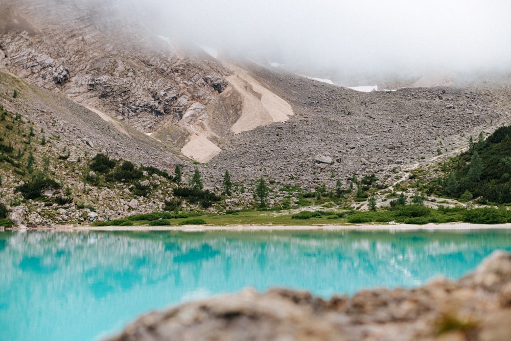 um lago azul cercado por montanhas e nuvens