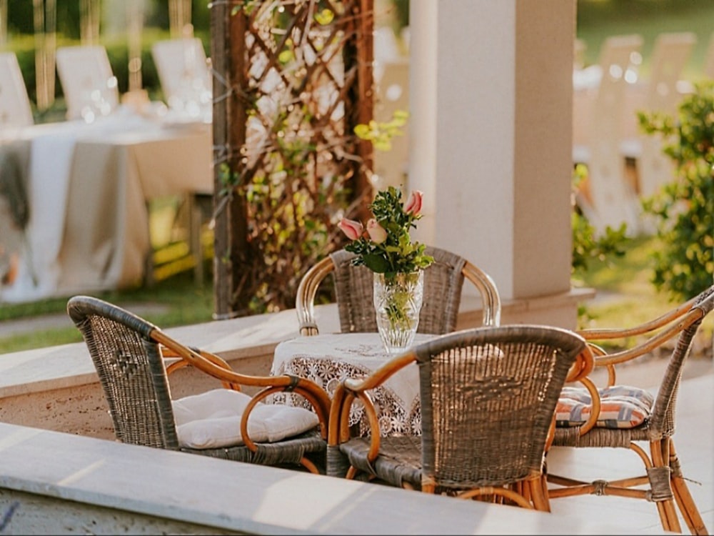 a table with chairs and a vase with flowers on it