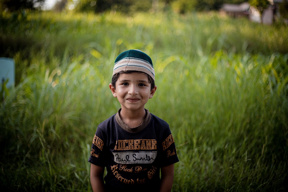 a young boy standing in a field of tall grass