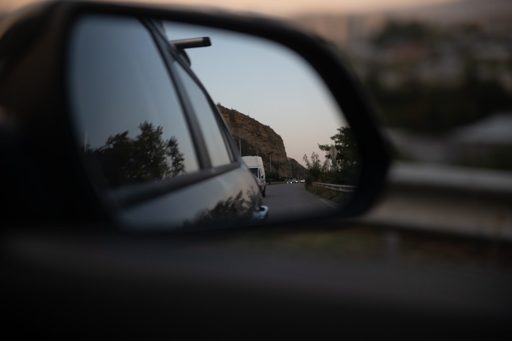 a car's side view mirror with a mountain in the background