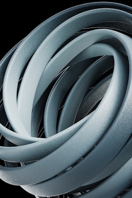 Intertwined, smooth loops form an abstract, sculptural shape with a metallic appearance against a black background.