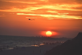 A vibrant sunset over the ocean with kiteboarders in action.