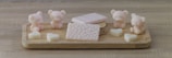 A collection of pastel-colored soaps and accessories displayed on a light wooden shelf.