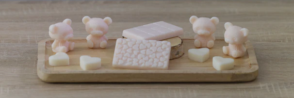 An overhead shot of a wooden tray holding various uniquely shaped soaps with star and moon imprints, surrounded by dried lavender and small crystals.