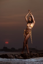 A graceful model dressed in chic beachwear against a sunset backdrop.