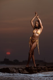 A graceful model dressed in chic beachwear against a sunset backdrop.