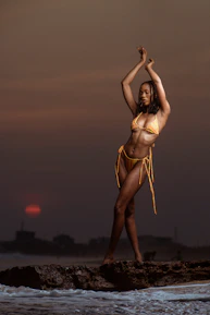 Model wearing a stylish luxury swimsuit by the beach at sunset