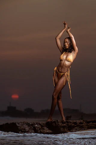 Model wearing a stylish luxury swimsuit by the beach at sunset
