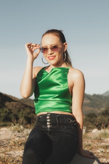 a woman in a green top sitting on a rock