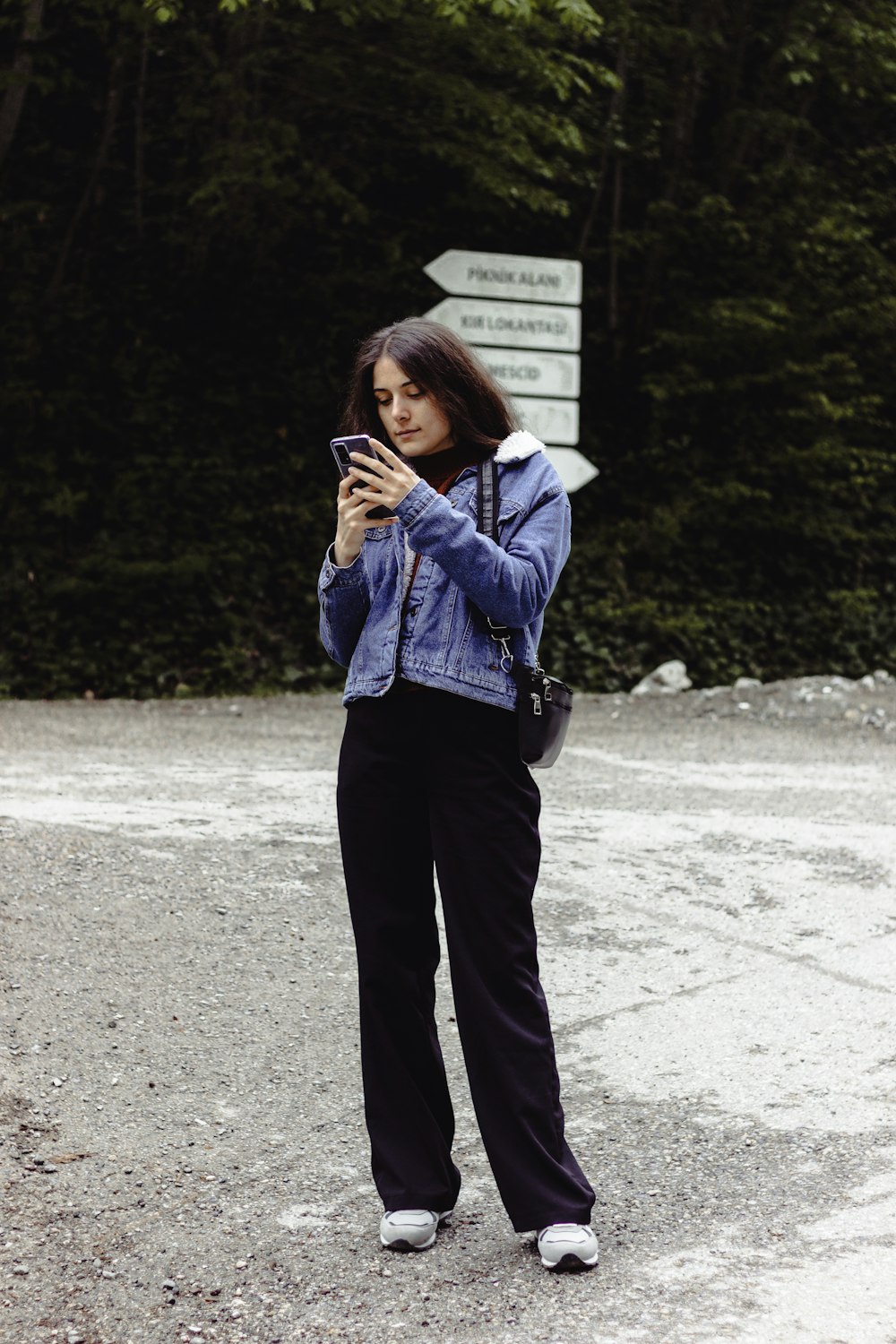 a woman standing in the middle of a road looking at her cell phone